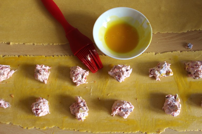 Schritt 4.) Bei Bedarf könnt ihr ein weiteres Eigelb verrühren und mit einem Pinsel rings um die Füllung auftragen - grade für Anfänger ist das ein guter Trick, dass die Nudeln gut halten.