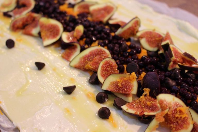 Breitet eure Teigplatte aus (kommt mit Backpapier), bestreicht sie sehr dünn mit ca. 3 EL Creme Fraiche und träufelt einen TL Honig darüber. Belegt sie in der Mitte mit 1 geraspelten Karotte, 100 g Blaubeeren, 3 gewaschenen, geschnittenen Feigen und ein paar Schokotropfen (2 EL)