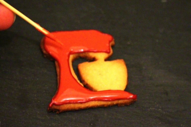 Ein zweiter Guss, der etwas heller und deutlich dünn flüssiger ist, "flutet" den Keks. Die Randschicht sorgt dafür, dass nichts verläuft. Mit einem Zahnstocher kriegt man kleinere Unebenheiten weg.